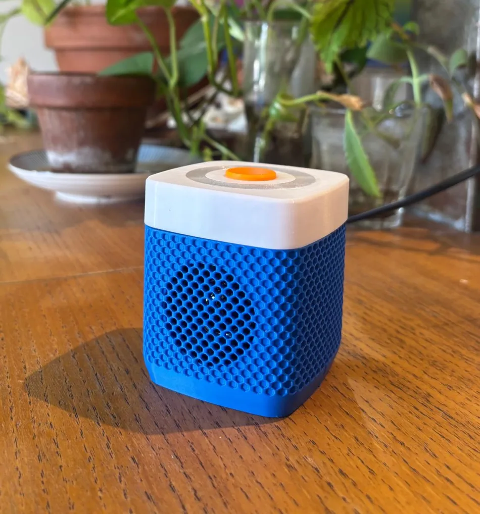 Amidou sitting on a living-room table: royal blue body, white lid, tangerine button
